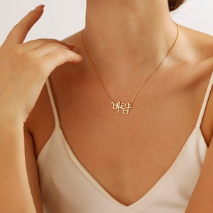 May include: A gold chain necklace with a pendant that says "바람" in Korean script.
