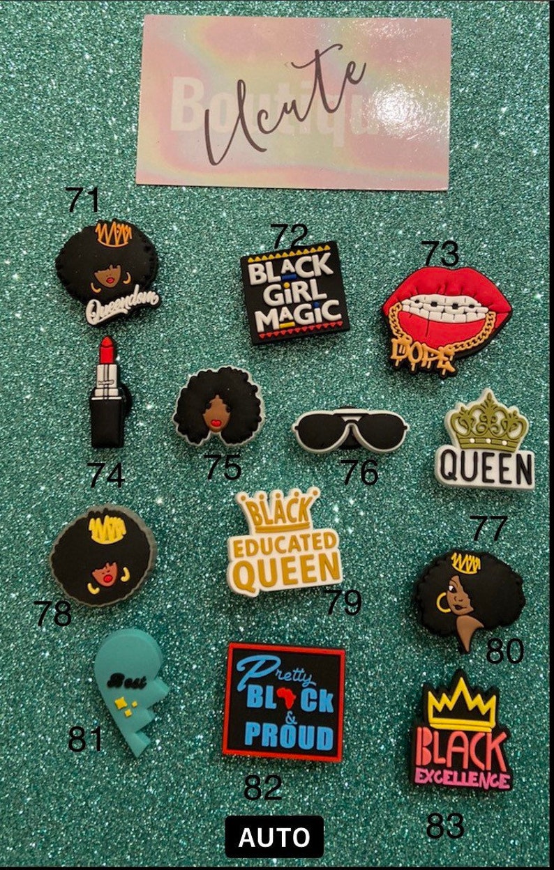 May include: A collection of thirteen colorful shoe charms featuring various designs including a red lipstick, black sunglasses, crowns, and text such as Black Girl Magic, Queen, Black Educated Queen, Pretty Black & Proud, and Black Excellence.