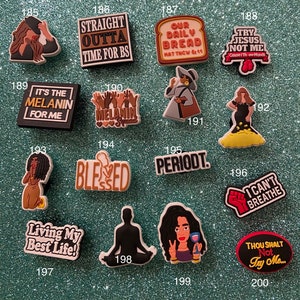 May include: A collection of sixteen colorful rubber shoe charms featuring various illustrations and text, including phrases like Straight Outta Time For BS, Our Daily Bread, It's The Melanin For Me, Melanin Squad, Blessed, Periodt, I Can't Breathe, Living My Best Life, and Thou Shalt Not Try Me.