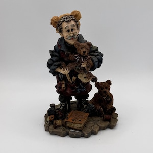 May include: A detailed figurine of a man holding two teddy bears, with a third bear seated at his feet. The man wears a dark coat and apron, with a mustache and bear-shaped ears. A book titled "Bears Bear Pattern Book" is visible.
