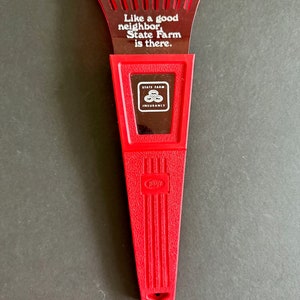 May include: Red plastic ice scraper with a white State Farm Insurance logo and the slogan "Like a good neighbor, State Farm is there."