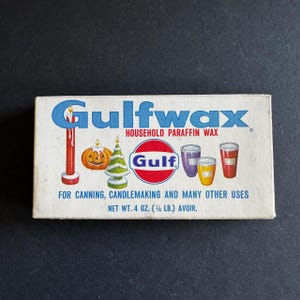 May include: A rectangular box of Gulfwax household paraffin wax. The box features the brand name in blue, a red candle, a jack-o'-lantern, a Christmas tree, and three colorful containers. The text reads "For canning, candlemaking and many other uses". Net weight 4 oz.