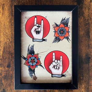 Puede incluir: Una impresión enmarcada con cuatro diseños de tatuaje tradicionales. Dos círculos rojos con una mano haciendo el gesto de rock and roll. Dos flores rojas y azules con hojas negras.