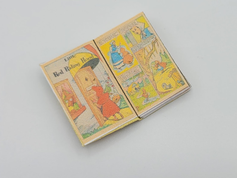 May include: An open book with the title "Little Red Riding Hood" on the cover. The book is illustrated with colorful cartoon images.