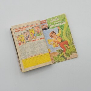 May include: An open book with a colorful cover featuring a boy climbing a beanstalk. The book's title is "Jack and the Beanstalk". The back cover features a colorful advertisement for "The Wonderful World of Fairy Tales".