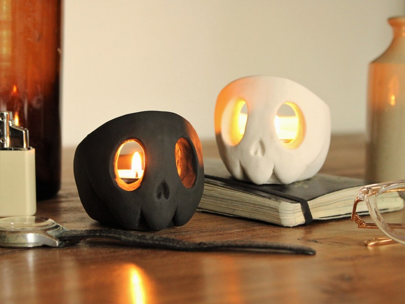Two cute styled skulls in black and white with a matte finish. The top of the head and eyes are hollow for candlelight.