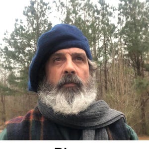 May include: A blue beret is worn by a person with a grey beard and a grey scarf. The person is wearing a plaid vest. The word "Blue" is written in the bottom of the image.