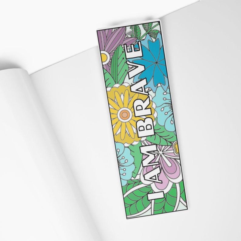 K&ouml;nnte beinhalten: Ein Lesezeichen mit einem floralen Design in Blaut&ouml;nen, Gr&uuml;n, Gelb und Rosa. Der Text "I AM BRAVE" ist in Wei&szlig; auf das Lesezeichen gedruckt.