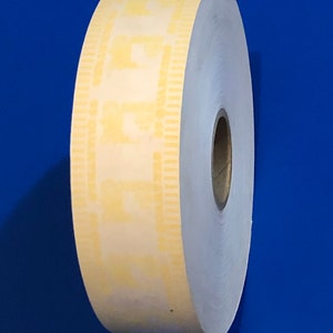 May include: A roll of white thermal paper with a yellow perforated edge. The paper is rolled up and has a brown core in the center.