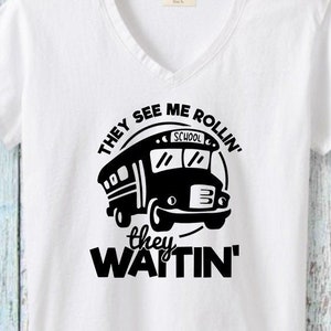 Puede incluir: Camiseta blanca con un gráfico negro de un autobús escolar y el texto "They see me rollin' they hatin'".