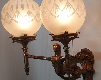 May include: A pair of antique brass wall sconces with frosted glass globes and a decorative female figure holding the sconces.