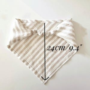 May include: A beige and white striped bandana, measuring 9.4 inches (24 cm) in length. The fabric is folded into a triangle shape with an elastic band at the top. The bandana is designed for pets.