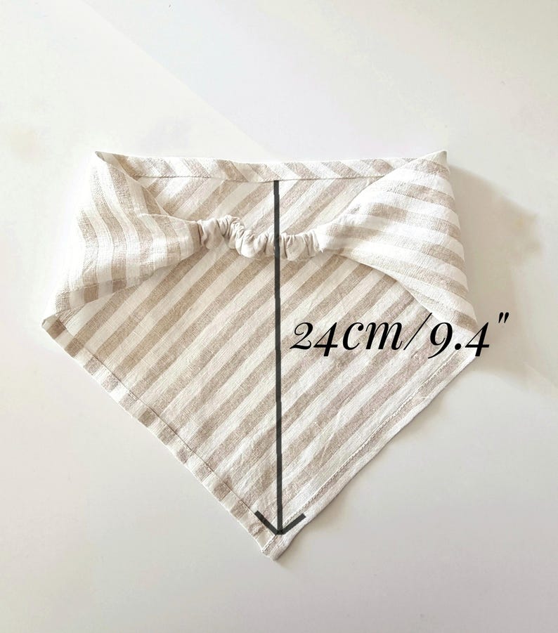 May include: A beige and white striped bandana, measuring 9.4 inches (24 cm) in length. The fabric is folded into a triangle shape with an elastic band at the top. The bandana is designed for pets.