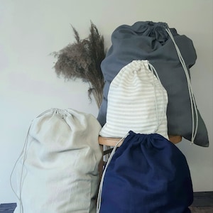 Op de afbeelding: Vier waszakken in verschillende kleuren en patronen. Een grijze zak, een witte zak met grijze strepen, een witte zak en een donkerblauwe zak.
