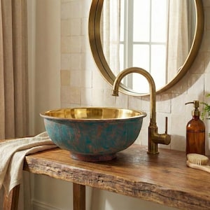 May include: A teal and gold bathroom sink on a wooden console, with a gold tap and round mirror above. A brown soap dispenser, brush, and plant are also visible, creating a rustic aesthetic.