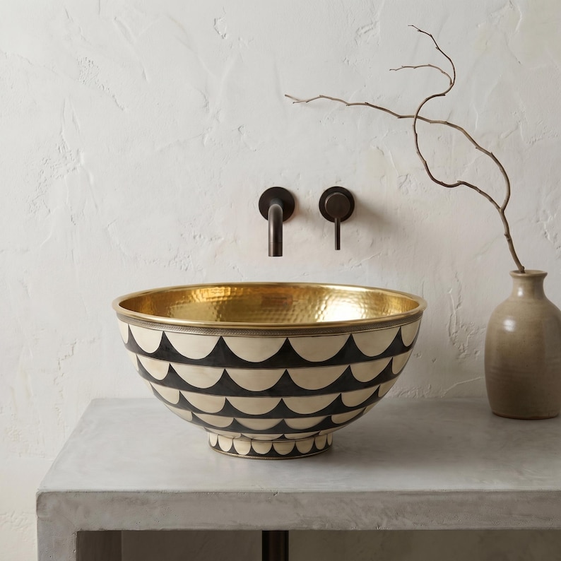 May include: A round vessel sink featuring a hammered gold interior and an exterior decorated with a repeating black and cream scalloped pattern. The sink is paired with a dark bronze wall-mounted faucet and a single handle control lever.