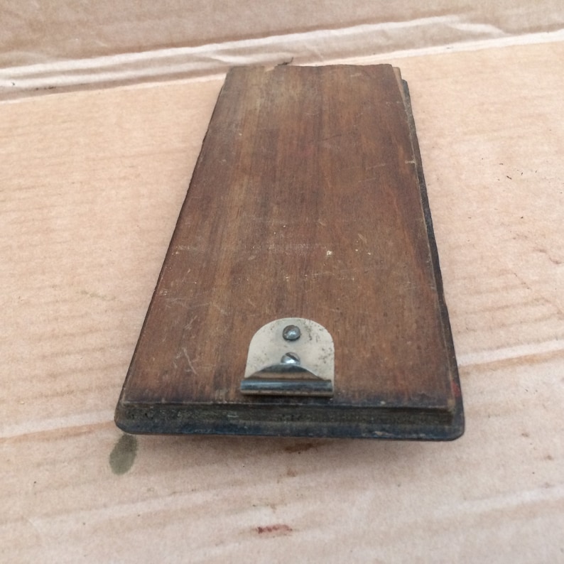 Pu&ograve; includere: Una cornice rettangolare in legno con un gancio di metallo sul retro. La cornice &egrave; di colore marrone scuro e ha una finitura usurata.
