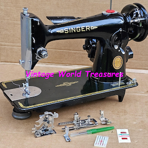 May include: Vintage Singer sewing machine, black with gold detailing, and various attachments. The machine has a silver needle bar and a red button. The base is black with gold trim. Accessories include presser feet, needles, and a green pen.