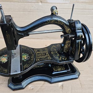 May include: Black vintage sewing machine with gold accents and the text "The Improved Dolly Varden" on the side.