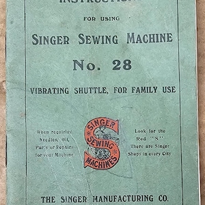 May include: Green instruction booklet for a Singer Sewing Machine No. 28. The booklet is titled "Instructions for Using Singer Sewing Machine No. 28 Vibrating Shuttle, for Family Use". The booklet was published in 1920 by The Singer Manufacturing Co.