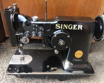 May include: A black Singer sewing machine with a gold logo and a serial number 107418. The machine has a large metal wheel and a needle.