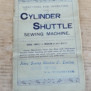 Peut inclure: Un manuel en papier vintage pour la machine à coudre Cylinder Shuttle de Jones' Sewing Machine Co. Limited. Le document présente un texte bleu sur fond gris clair, incluant des instructions d'utilisation, de commande de pièces et des détails.