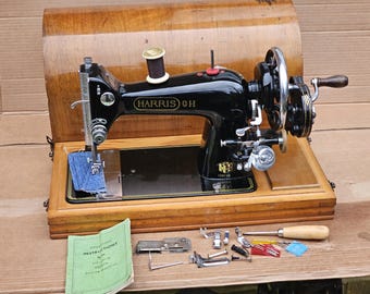 Puede incluir: Una máquina de coser vintage HARRIS 9H negra en una caja de madera con una bobina de hilo, un pedal y un juego de accesorios para máquina de coser.