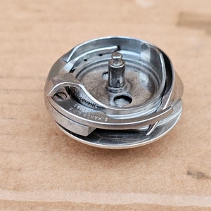 May include: A silver sewing machine bobbin winder with the text "HANSE U.S.A. PATENTED" on the side.