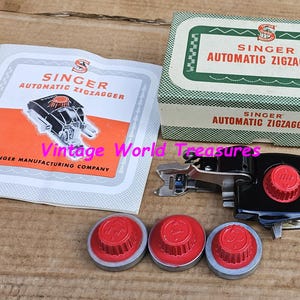 Puede incluir: Un juego de accesorios para máquinas de coser Singer Automatic Zigzagger vintage. El juego incluye el accesorio, tres diales rojos y plateados, una caja y una hoja de instrucciones. La caja y la hoja de instrucciones presentan el logotipo y el nombre del producto Singer.