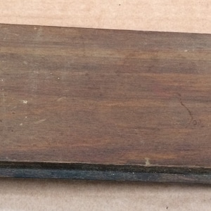 Pu&ograve; includere: Una scatola di legno con una chiusura in metallo. La scatola &egrave; marrone e ha una venatura di legno scuro. La chiusura &egrave; argentata e ha due piccoli fori.
