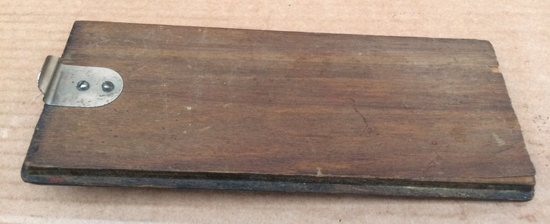 Pu&ograve; includere: Una scatola di legno con una chiusura in metallo. La scatola &egrave; marrone e ha una venatura di legno scuro. La chiusura &egrave; argentata e ha due piccoli fori.
