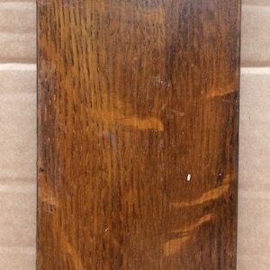 Pu&ograve; includere: Un cartello rettangolare in legno con una macchia marrone scuro. Il cartello ha un solo pomello rotondo al centro.