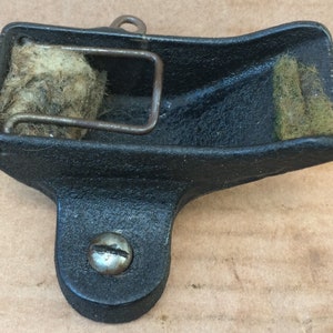 Op de afbeelding: Zwarte metalen luchtfilter met een bruin en wit filterelement en een metalen veer. De filter heeft een schroef aan de onderkant.
