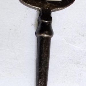 Può includere: Una chiave vintage in metallo marrone scuro con un arco a forma di cuore e un lungo fusto dritto.