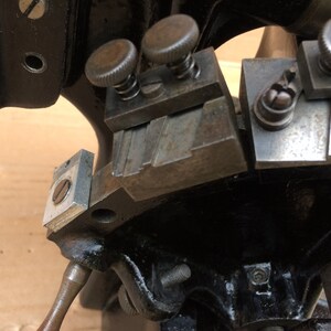 Puede incluir: Primer plano de una herramienta de metal con m&uacute;ltiples partes ajustables. La herramienta tiene un acabado plateado y est&aacute; hecha de metal. La herramienta tiene una serie de ranuras ajustables y una perilla para apretar.