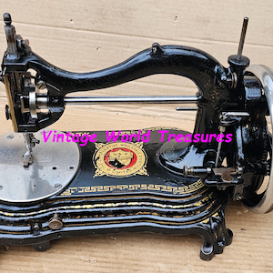 May include: A vintage black sewing machine with gold accents. The machine features a curved arm, a silver hand wheel, and a decorative base. The text "Vintage World Treasures" is visible on the machine.
