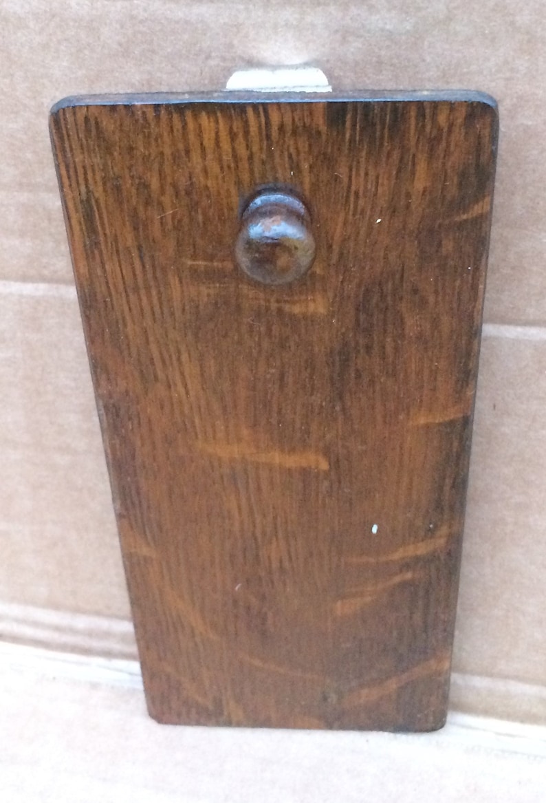 Pu&ograve; includere: Un fermaporta in legno marrone scuro con un pomo rotondo. Il fermaporta ha una venatura del legno naturale.