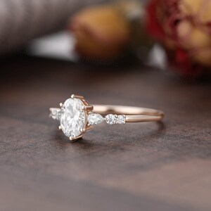 May include: A rose gold engagement ring with a large oval-shaped center stone and smaller pear-shaped accent stones.
