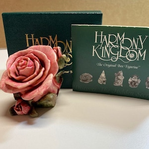 May include: A pink rose figurine with green leaves, part of the Harmony Kingdom "The Original Box Figurine" collection. The figurine is displayed on a green box with the Harmony Kingdom logo.