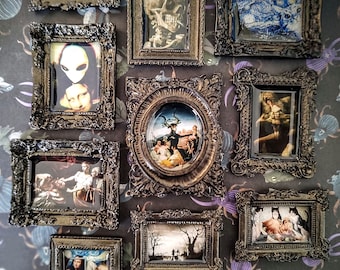 May include: A collection of 10 small, ornate, black picture frames with various images inside. The frames are arranged in a grid pattern on a dark background with a repeating pattern of insects and flowers. The images include a skull, a starry night sky, a woman's face, a group of people, a forest scene, and a cat.