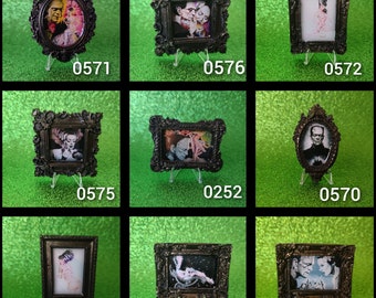 May include: Nine ornate black picture frames with various images of people and monsters. The frames are on small stands and are arranged in a grid pattern.