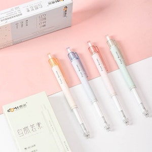 Puede incluir: Cuatro bolígrafos con barriles transparentes y acentos en colores pastel, incluyendo naranja, azul, rosa y verde. Cada bolígrafo tiene el texto "From Nature" impreso en el lateral. También se ve una caja blanca con caracteres chinos y la marca "COMI".