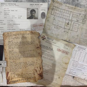 May include: A collection of fictional Umbrella Corporation documents including an inmate record card for Robert McAllister, a facility floor plan, a security file, a duty schedule, and a handwritten, stained diary entry dated from May 18th to May 27th.