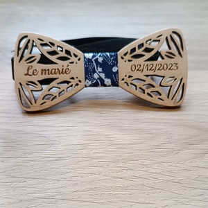 Peut inclure: Un nœud papillon en bois avec un motif floral et le texte "Le marié" et "02/12/2023" gravé dessus.