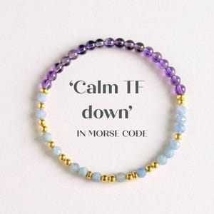 May include: A bracelet featuring purple amethyst and pale blue aquamarine beads, with gold-coloured spacers. The image includes the text: 'Calm TF down' IN MORSE CODE.