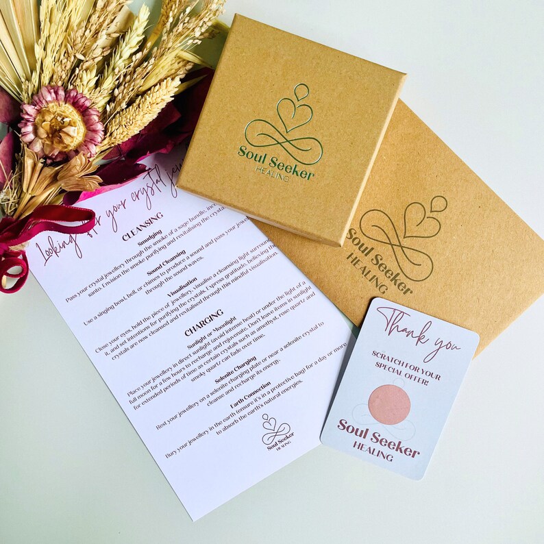 May include: A brown box with a white label that says "Soul Seeker Healing" and a pink heart symbol. The box is open and a white card with the text "Thank you" and "Scratch for your special offer" is visible. The card has a pink circle with the text "Soul Seeker Healing" in white.