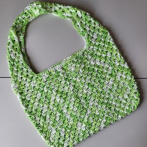 Pu&ograve; includere: Una borsa tote all'uncinetto con un motivo verde e bianco. La borsa presenta un manico largo e integrato e un design a punto strutturato. La borsa &egrave; realizzata in filato morbido ed &egrave; adatta per trasportare vari oggetti.