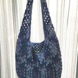 Pu&ograve; includere: Una borsa tote all'uncinetto blu con un motivo a granny square. La borsa presenta lunghe cinghie e un interno spazioso. Il design a trama aperta aggiunge un tocco di consistenza. Un accessorio elegante e pratico.