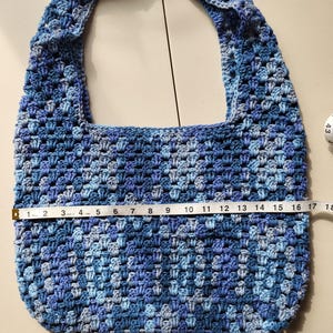 Pu&ograve; includere: Borsa all'uncinetto fatta a mano nei toni del blu. La borsa misura circa 43 cm di larghezza, con un motivo a punto strutturato e un'ampia tracolla. La palette di colori comprende blu chiari e scuri.