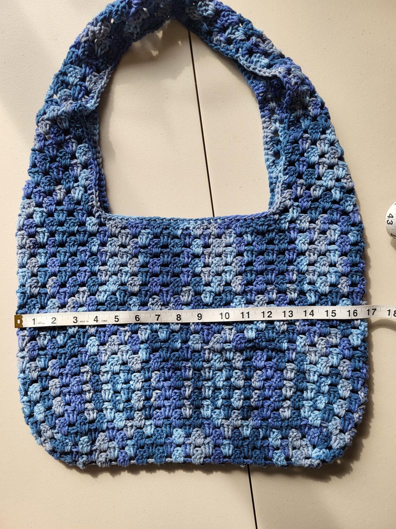 Pu&ograve; includere: Borsa all'uncinetto fatta a mano nei toni del blu. La borsa misura circa 43 cm di larghezza, con un motivo a punto strutturato e un'ampia tracolla. La palette di colori comprende blu chiari e scuri.